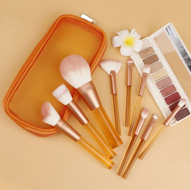 Make-up-Pinsel-Set mit transparenten, orangefarbenen Griffen, rosa Borsten, in einer orangefarbenen Tasche. Mit Lidschatten-Palette.