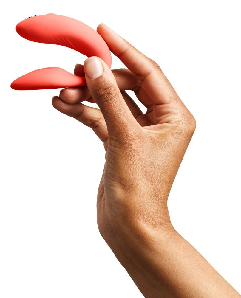 Hand hält korallenfarbenes Wellness-Produkt. Produkt in gebogener Form.