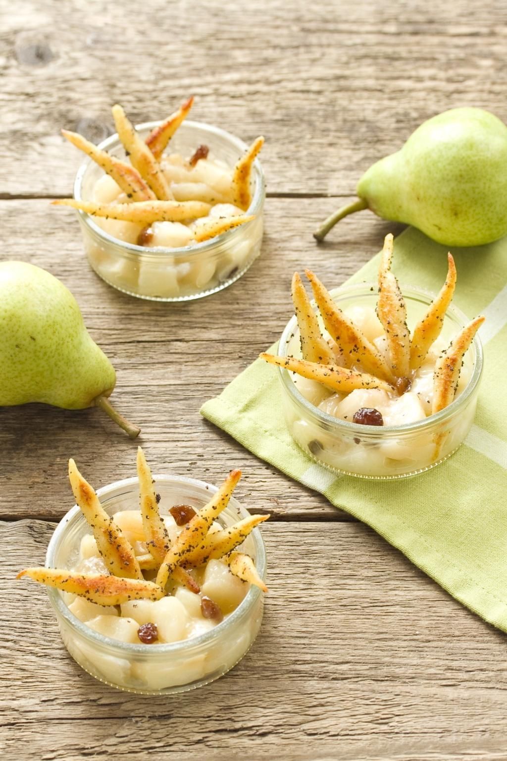Drei Gläser mit Dessert. Birnen, Rosinen, und knusprige Streifen. Auf Holzuntergrund.