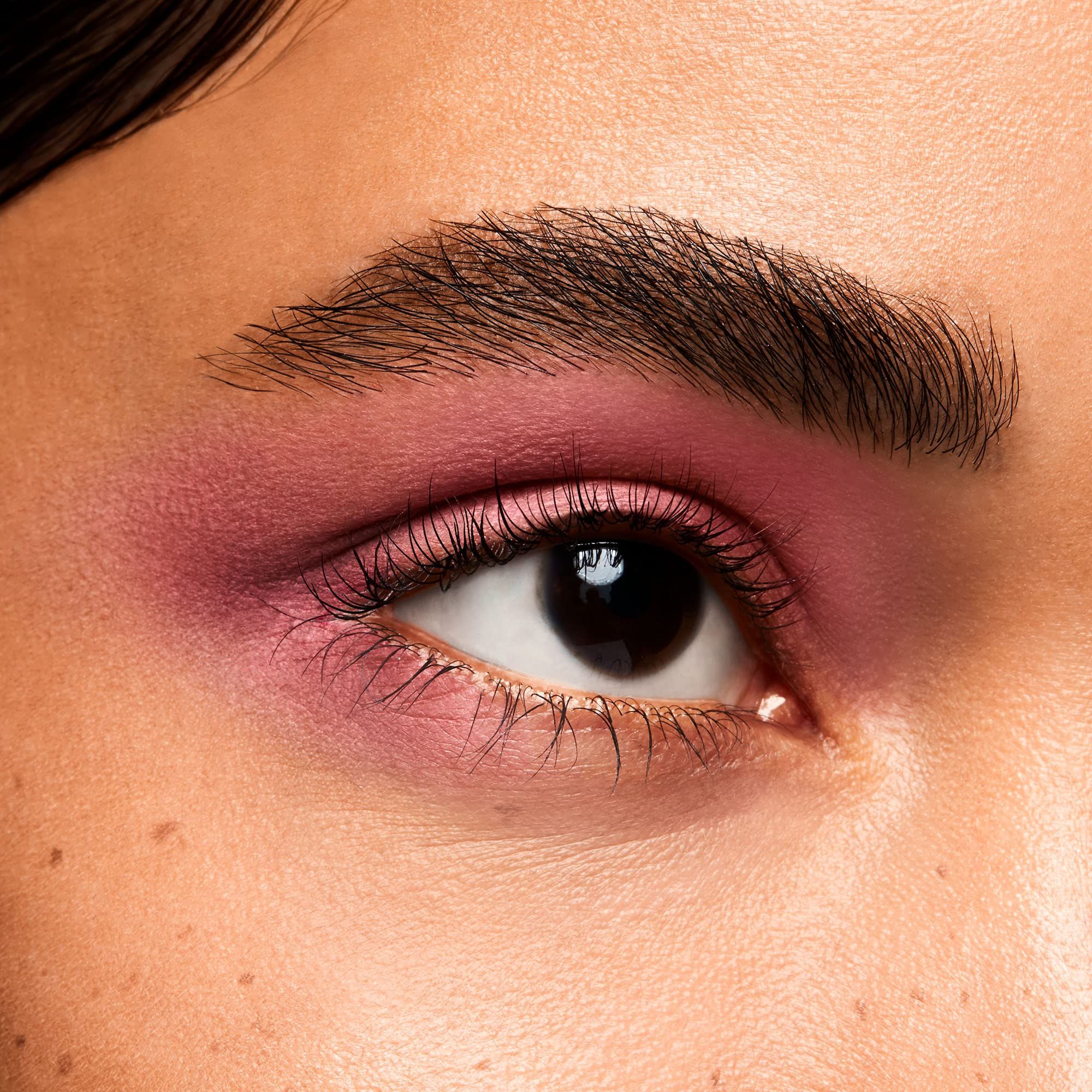 Auge mit rosa Lidschatten. Braune Augenbraue, Wimpern. Nahaufnahme.