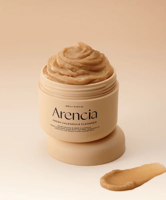 Beige Creme in einem offenen Tiegel. Aufschrift: Arencia, Fresh Calendula Cleanser. Daneben ein Klecks Creme.