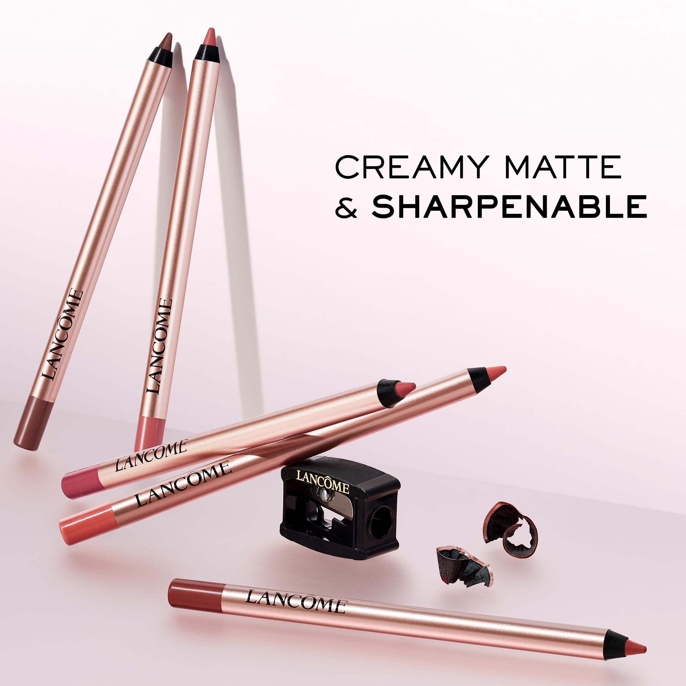 Mehrere Lipliner mit roségoldfarbenen Hüllen und einem Spitzer. Aufgedruckt ist der Markenname LANCOME. Text: Creamy Matte & Sharpenable.