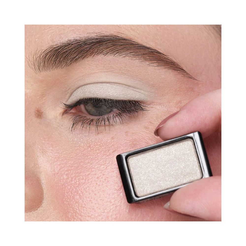 Auge mit aufgetragenem Lidschatten. Rechteckiger Lidschattenbehälter in der Hand.