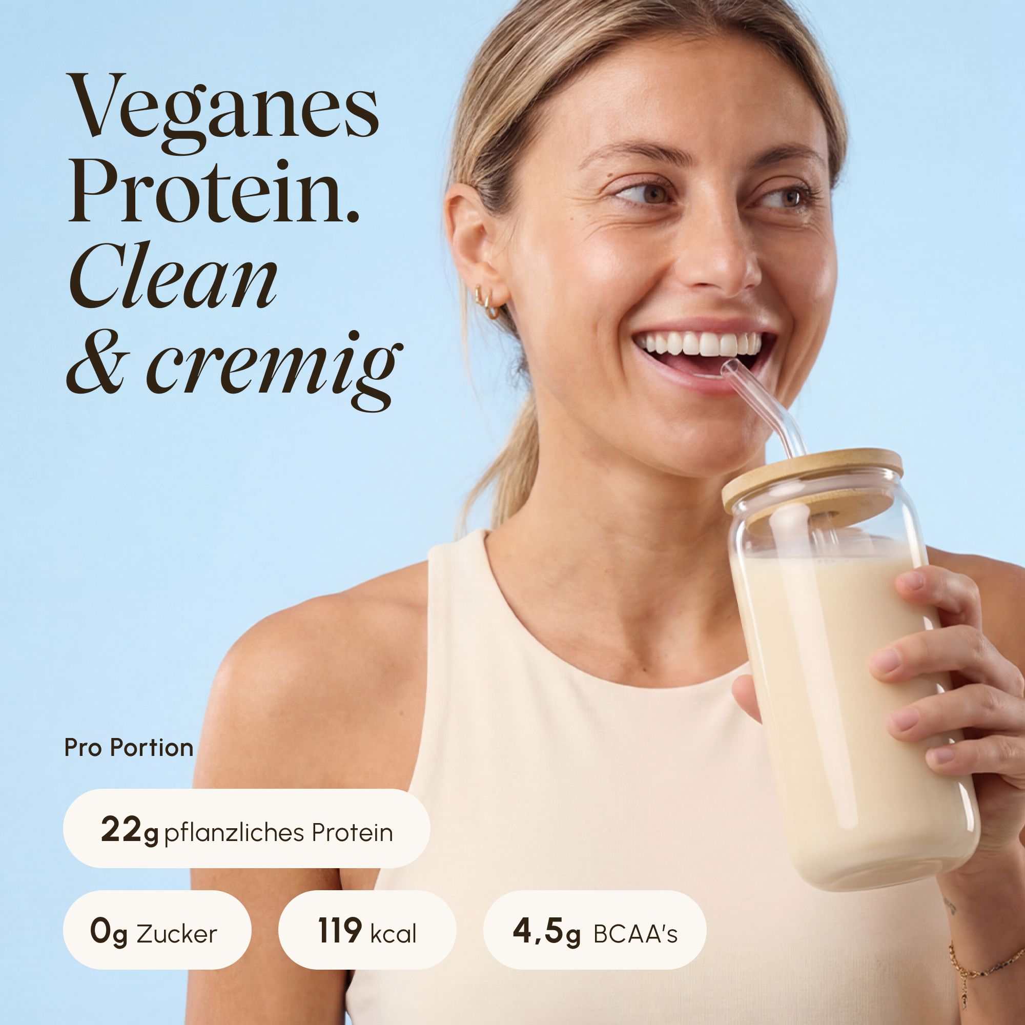 Frau trinkt cremigen veganen VETAIN Proteinshake aus Glas mit Strohhalm.