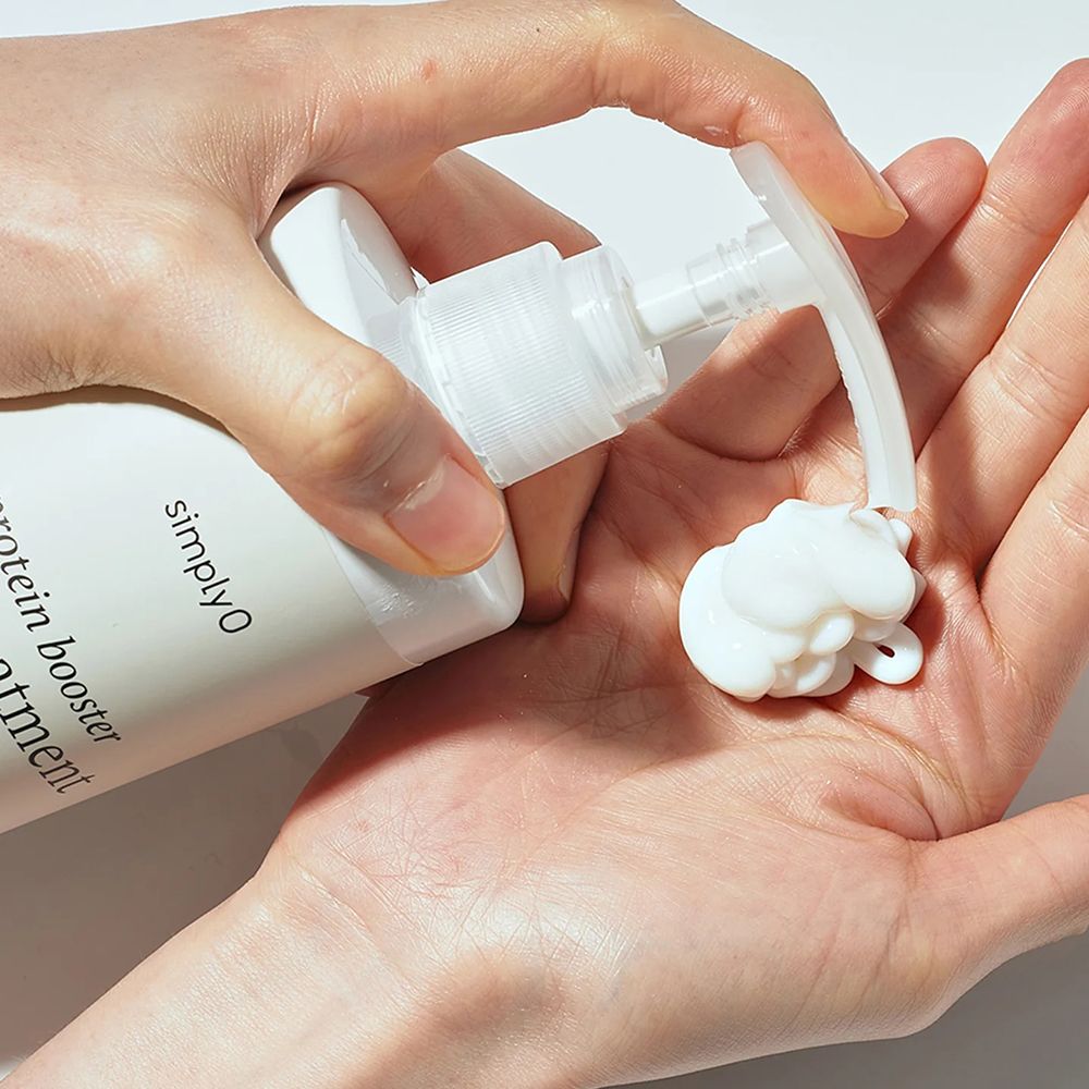 Weiße Flasche mit Pumpe, Produkt wird in die Hand gedrückt. Produktname: "simply O Protein Booster Hair Treatment".