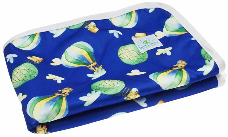 Blaue, wasserdichte Wickelunterlage mit Ballon-Motiv. Weißer Rand, Blümchen-Logo. Gefaltet.