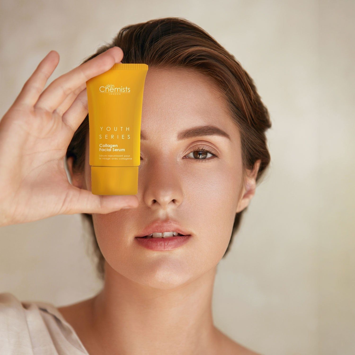 Frau hält gelbe Tube vor dem Gesicht. Aufschrift "skinChemists" und "Youth Series Collagen Facial Serum" sichtbar.