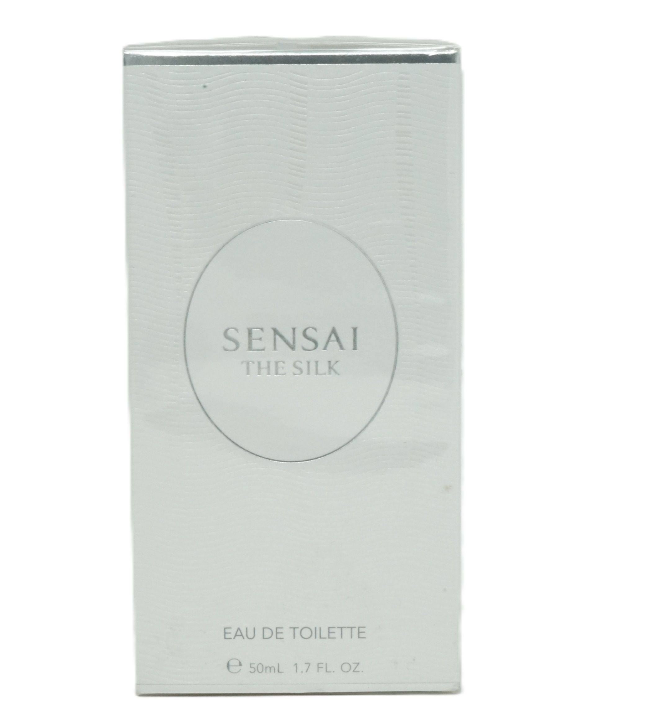 Weiße rechteckige Verpackung. Auf der Vorderseite steht in einem Kreis "SENSAI THE SILK". Darunter "EAU DE TOILETTE".