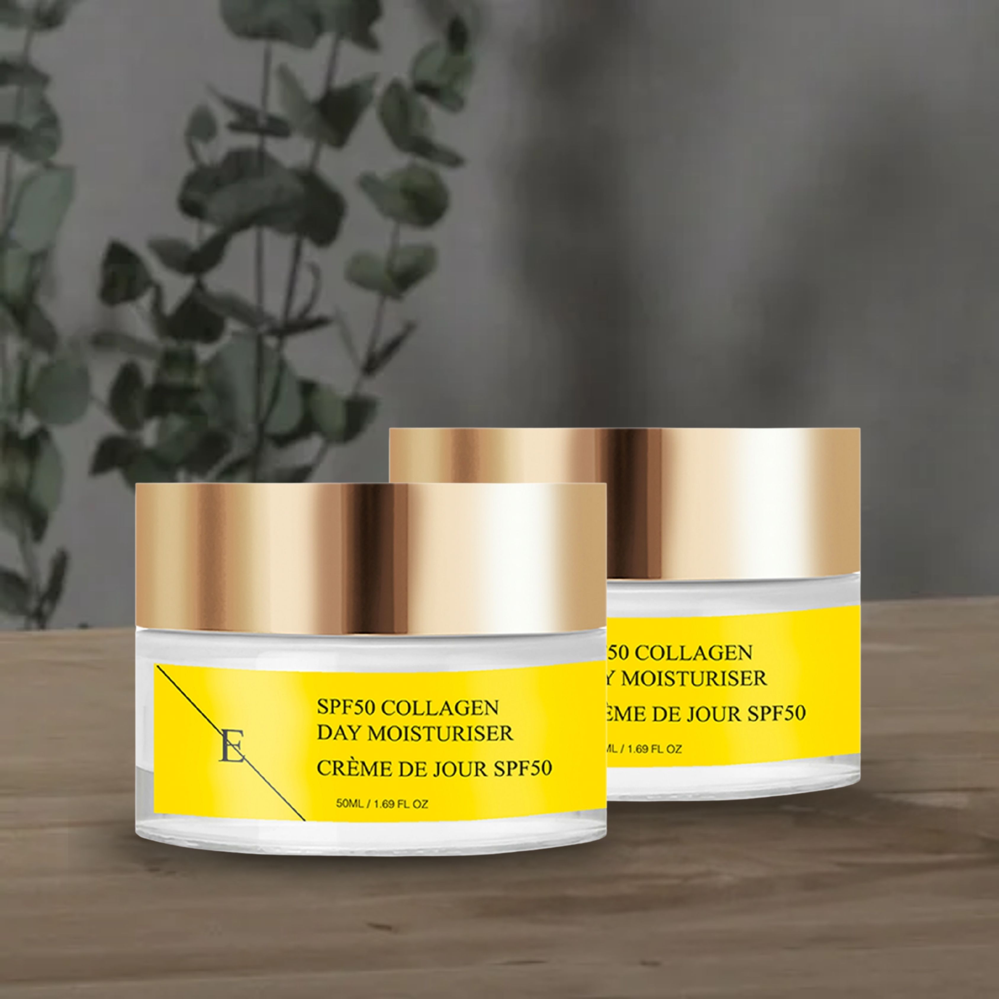 Zwei Tiegel SPF50 Kollagen Tagescreme. Gelbe Etiketten mit Text. Goldfarbene Deckel. Aufschrift: SPF50 Collagen Day Moisturiser. Vor grauem Hintergrund.
