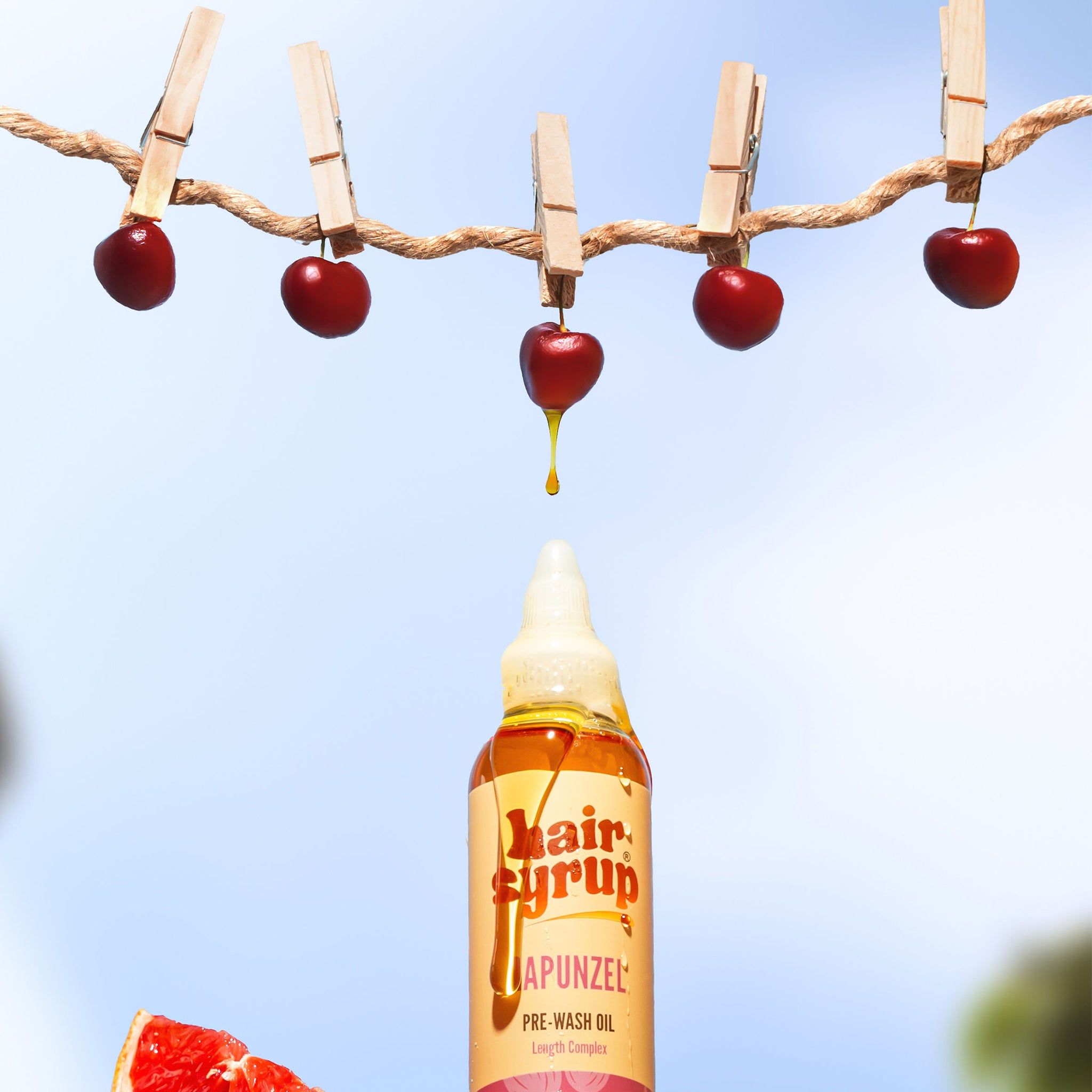 Hair Syrup Rapunzel Pre-Wash Oil-Flasche mit Kirschen an einer Schnur. Roter Hintergrund.