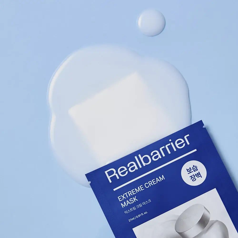 Blaues Sachet mit Produktabbildung und Text: Real Barrier Extreme Cream Mask. Auf blauem Hintergrund mit Flüssigkeit.
