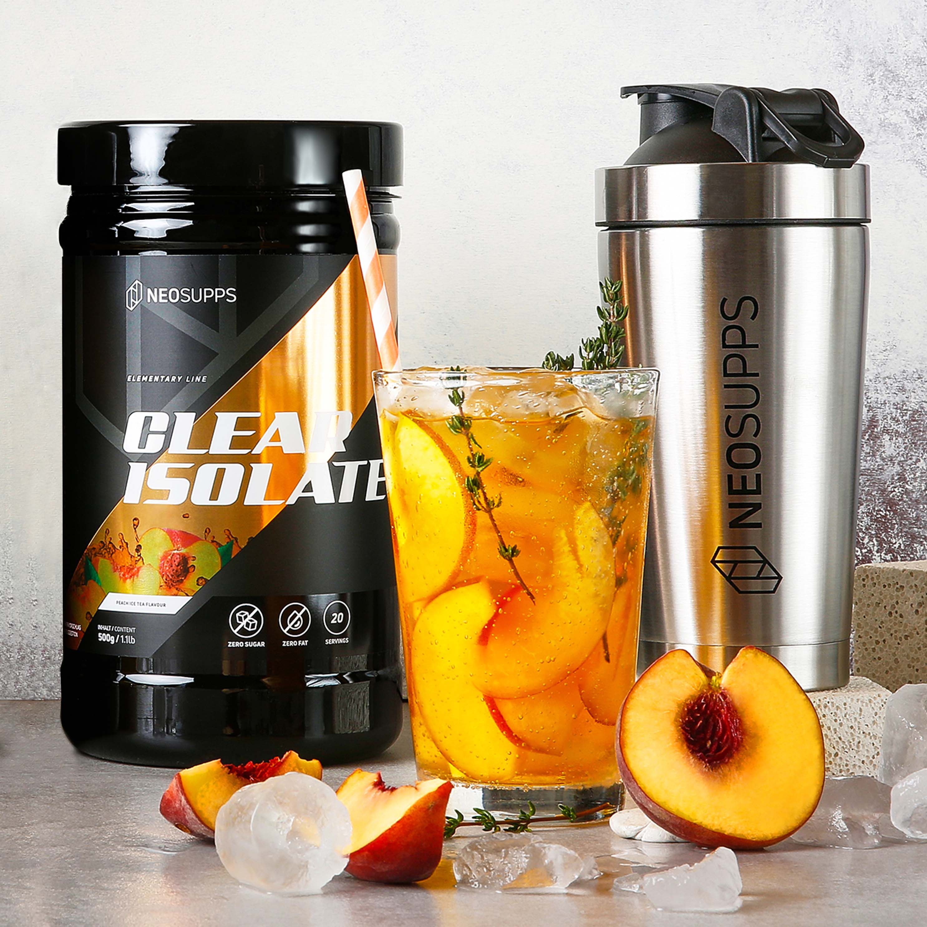 Schwarze Dose "CLEAR ISOLATE" neben Glas mit Getränk und Shaker. Pfirsichstücke und Eiswürfel.