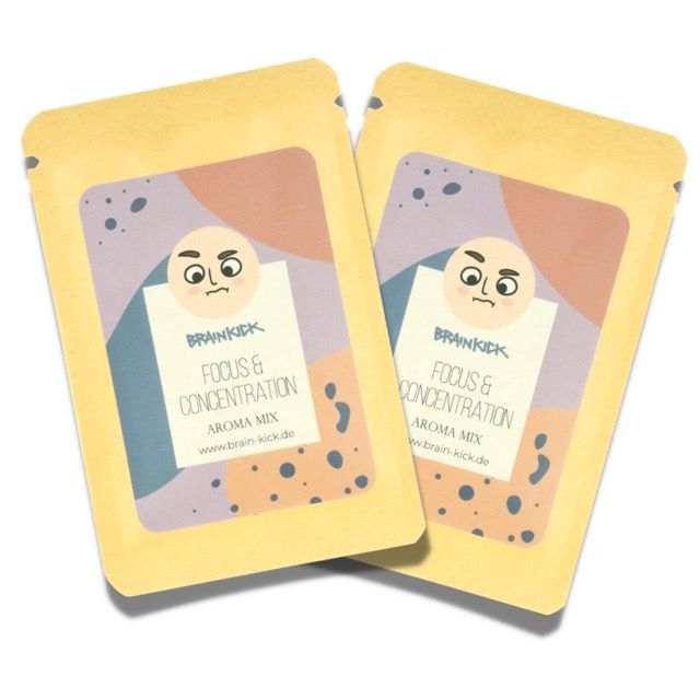Zwei gelbe Beutel mit Aufdruck. Text: Fokus & Konzentration, Aroma Mix. Marke: BrainKick. www.brain-kick.de. Illustration eines Gesichts.