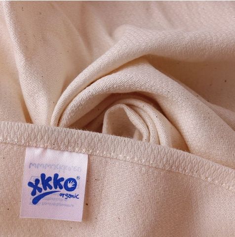 Beige Stoffwindel, gefaltet. Label mit Logo und Schriftzug "xkko organic". Baumwollstoff mit sichtbarer Struktur.