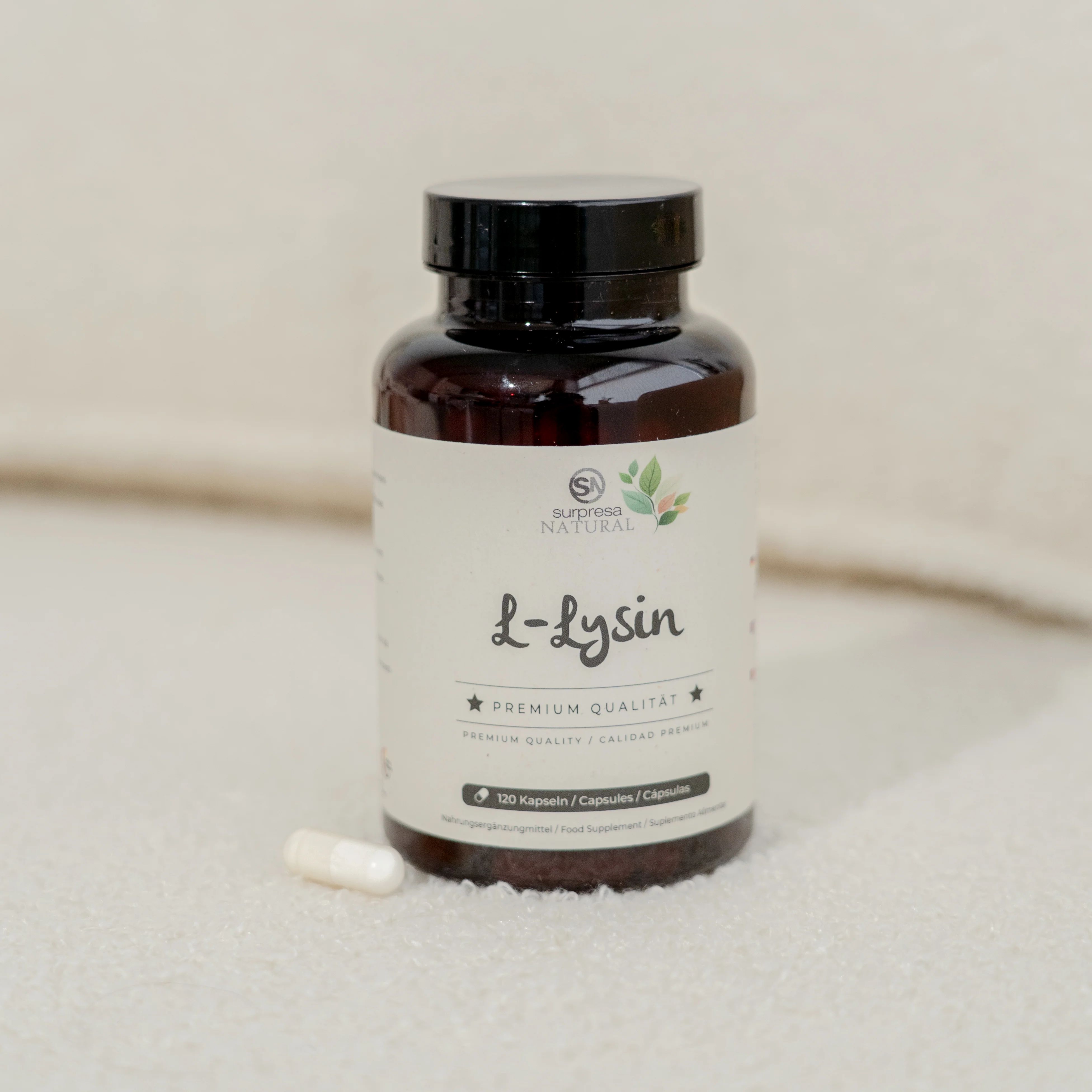 Braune Flasche mit weißen Kapseln. Aufschrift: Surpresa Natural L-Lysin, Premium Qualität. 120 Kapseln. Eine Kapsel liegt daneben.