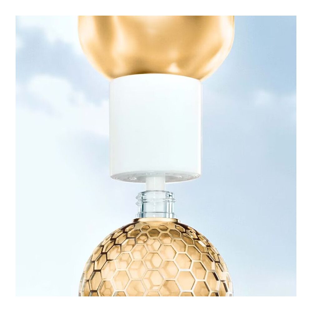 Goldfarbener Flakon mit wabenförmigem Muster. Weißer Verschluss wird aufgesetzt. Glasflasche.