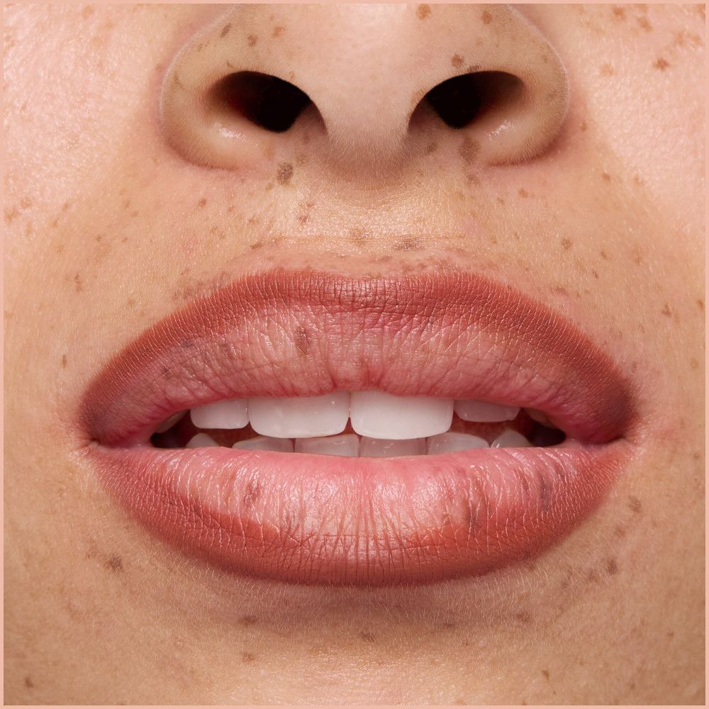 Nahaufnahme von Lippen mit Lippenstift. Haut mit Sommersprossen.