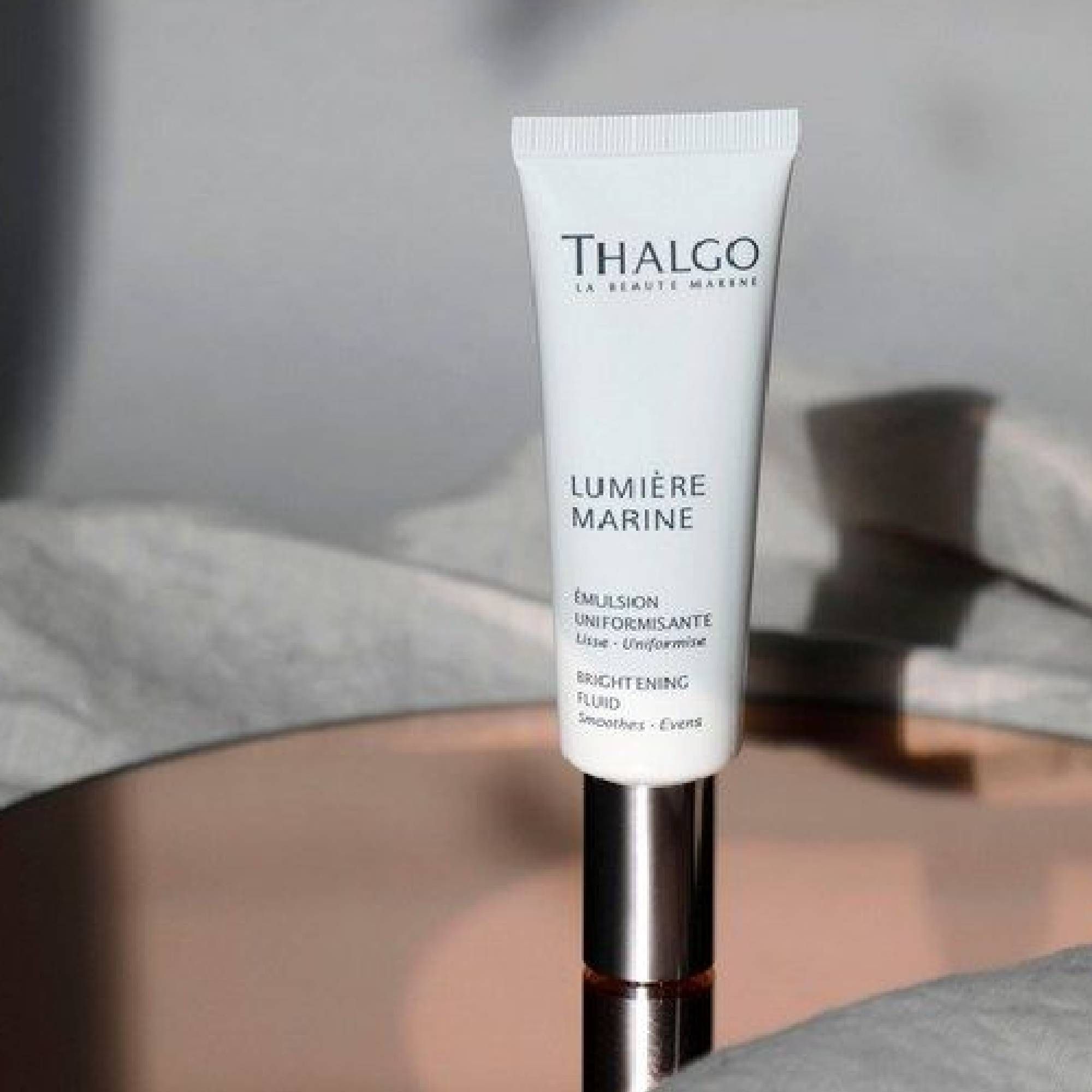 Weiße Tube mit silbernem Verschluss. Aufschrift: THALGO, LUMIÈRE MARINE, EMULSION UNIFORMANTE, BRIGHTENING FLUID.