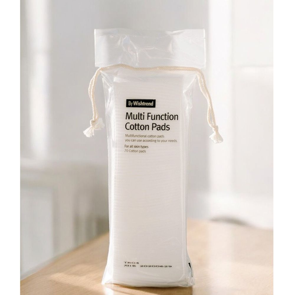 Verpackung mit Wattepads. Aufschrift: By Wishtrend Multi Function Cotton Pads. 70 Pads. Transparente Verpackung mit Kordelzug. Auf Tisch.
