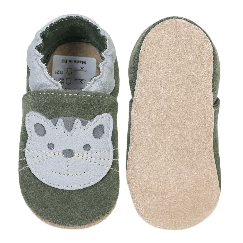 Olivgrüne Babyschuhe mit Katzenmotiv. Ein Schuh von oben, einer von unten. Wildleder, weißer Rand, Katzenkopf. Helle Ledersohle.