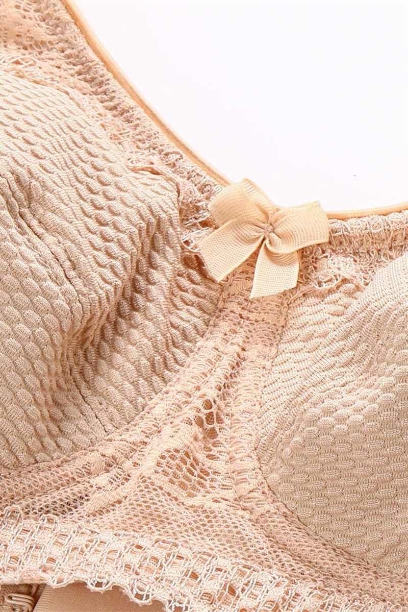 Nahaufnahme des BHs. Beige Farbe, strukturiertes Material, Spitze und Schleife.