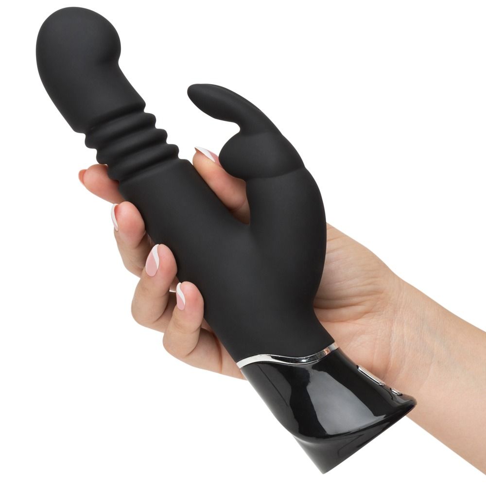 Hand hält schwarzen Vibrator mit geripptem Schaft und Hasenohren-Aufsatz. Glänzender Sockel mit Bedienelementen.