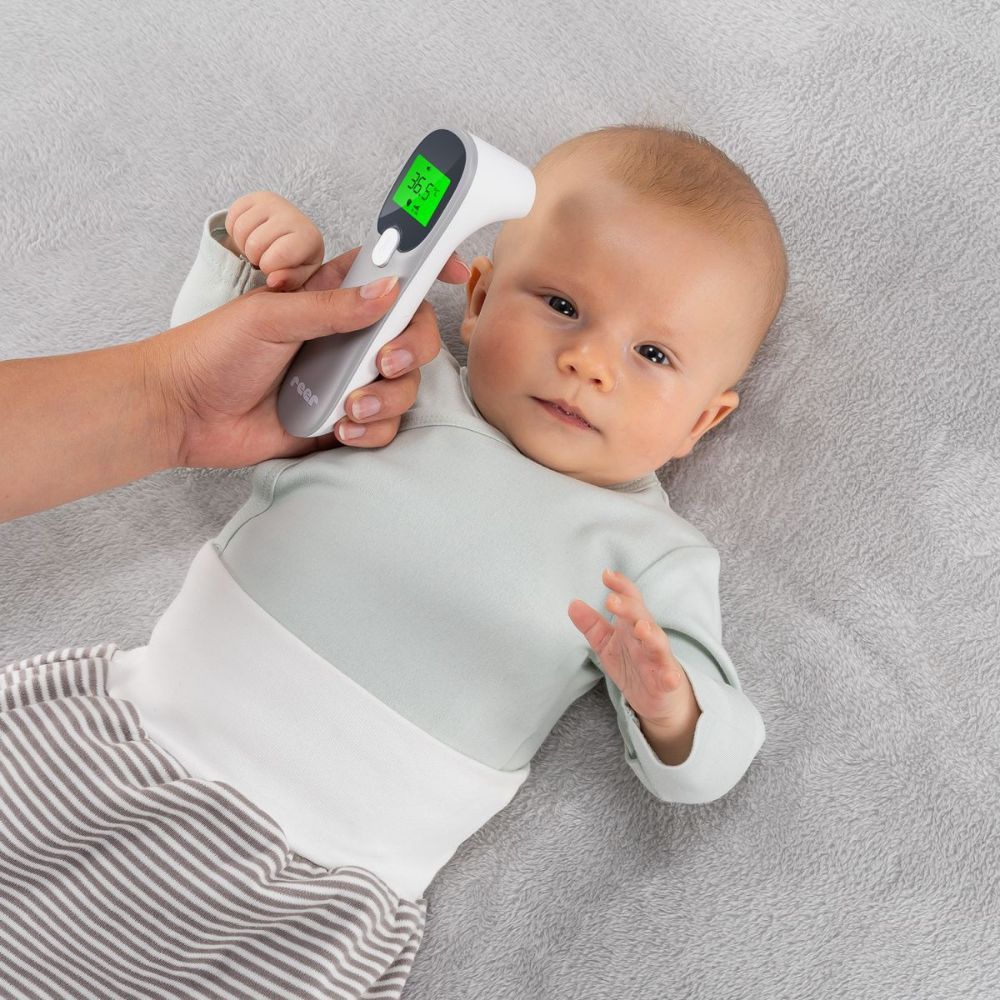 Person misst mit dem Infrarot-Thermometer die Temperatur eines Babys. Das Display zeigt 36,5°C.
