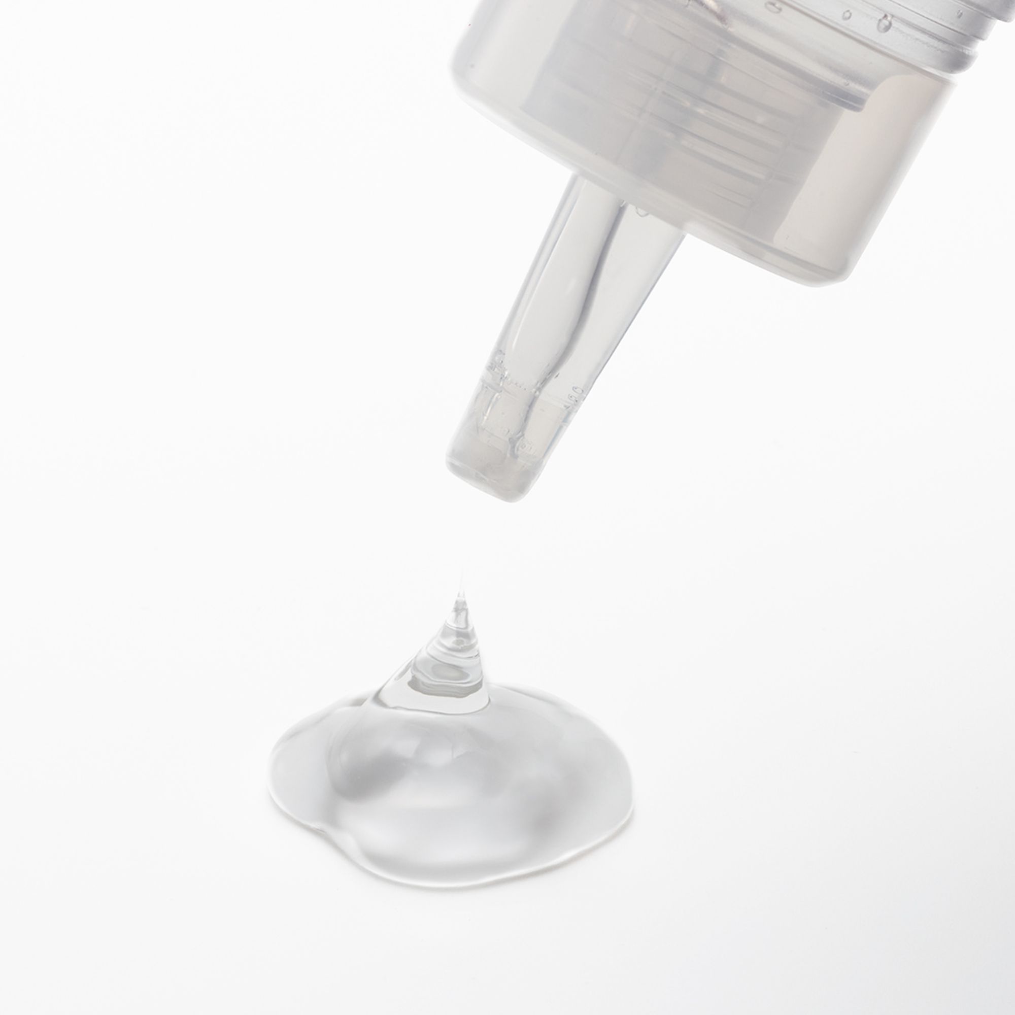 Klare Flüssigkeit tropft aus einer Düse auf eine Oberfläche. Flüssigkeit bildet einen kleinen Tropfen.