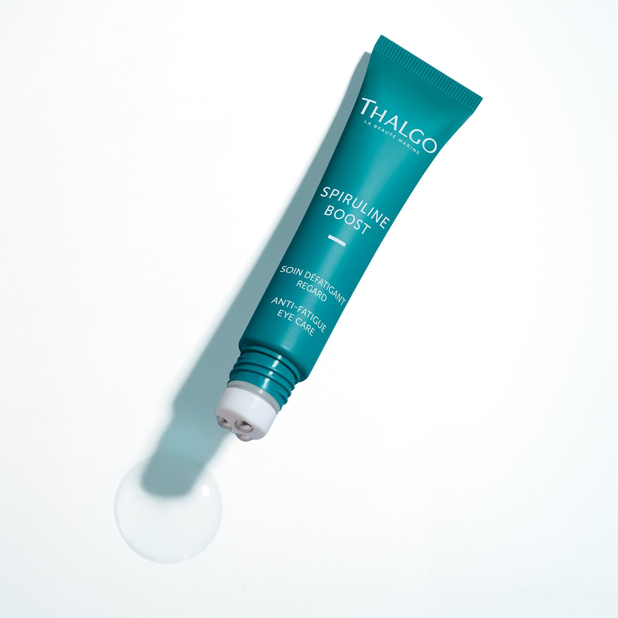 Türkisfarbene Tube mit Roll-on-Applikator. Aufschrift: THALGO, Spiruline Boost, Anti-Fatigue Eye Care. Tropfen daneben.