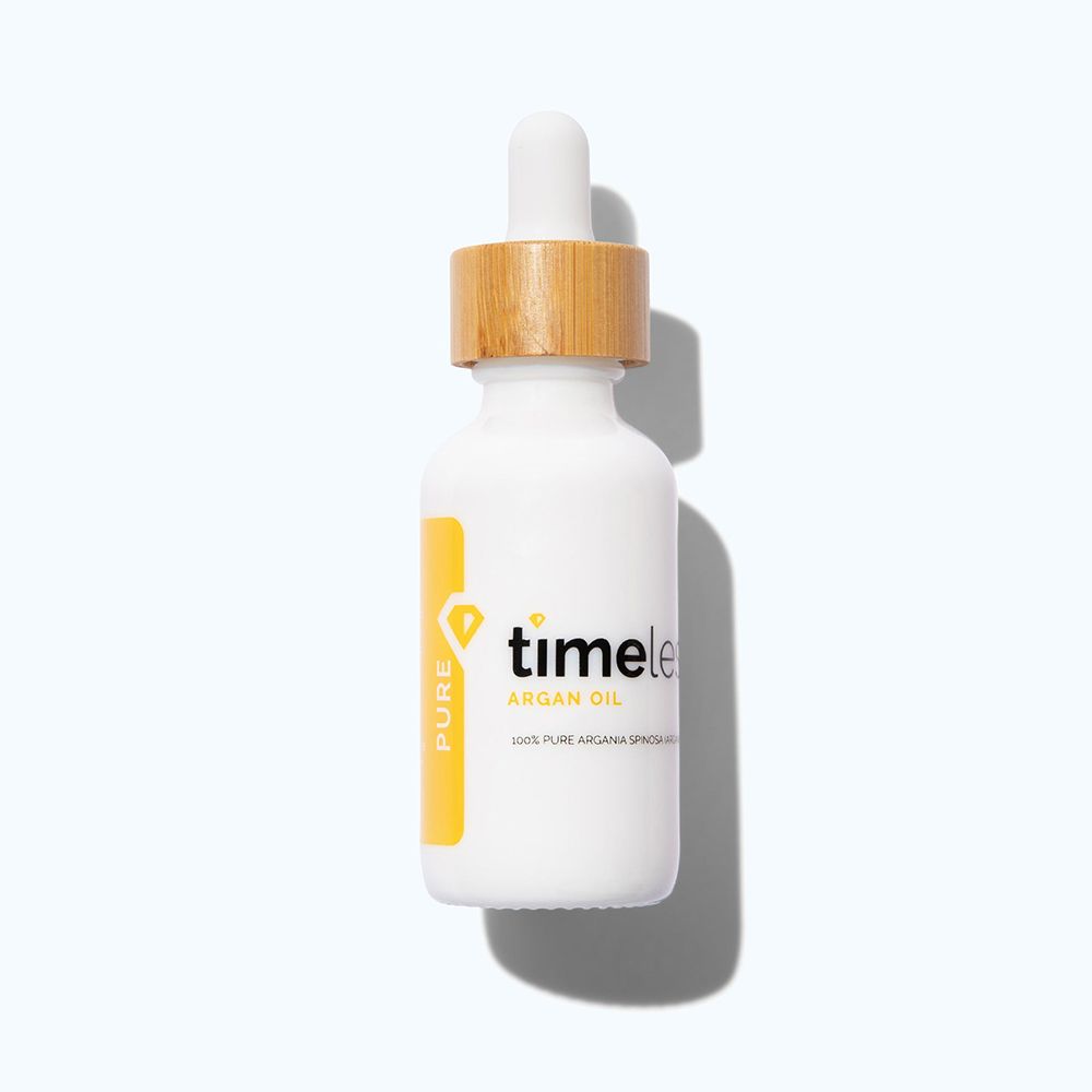 Weiße Flasche mit Holzdeckel und Pipette. Gelbes Etikett mit "timeless" und "Argan Oil" Schriftzug.