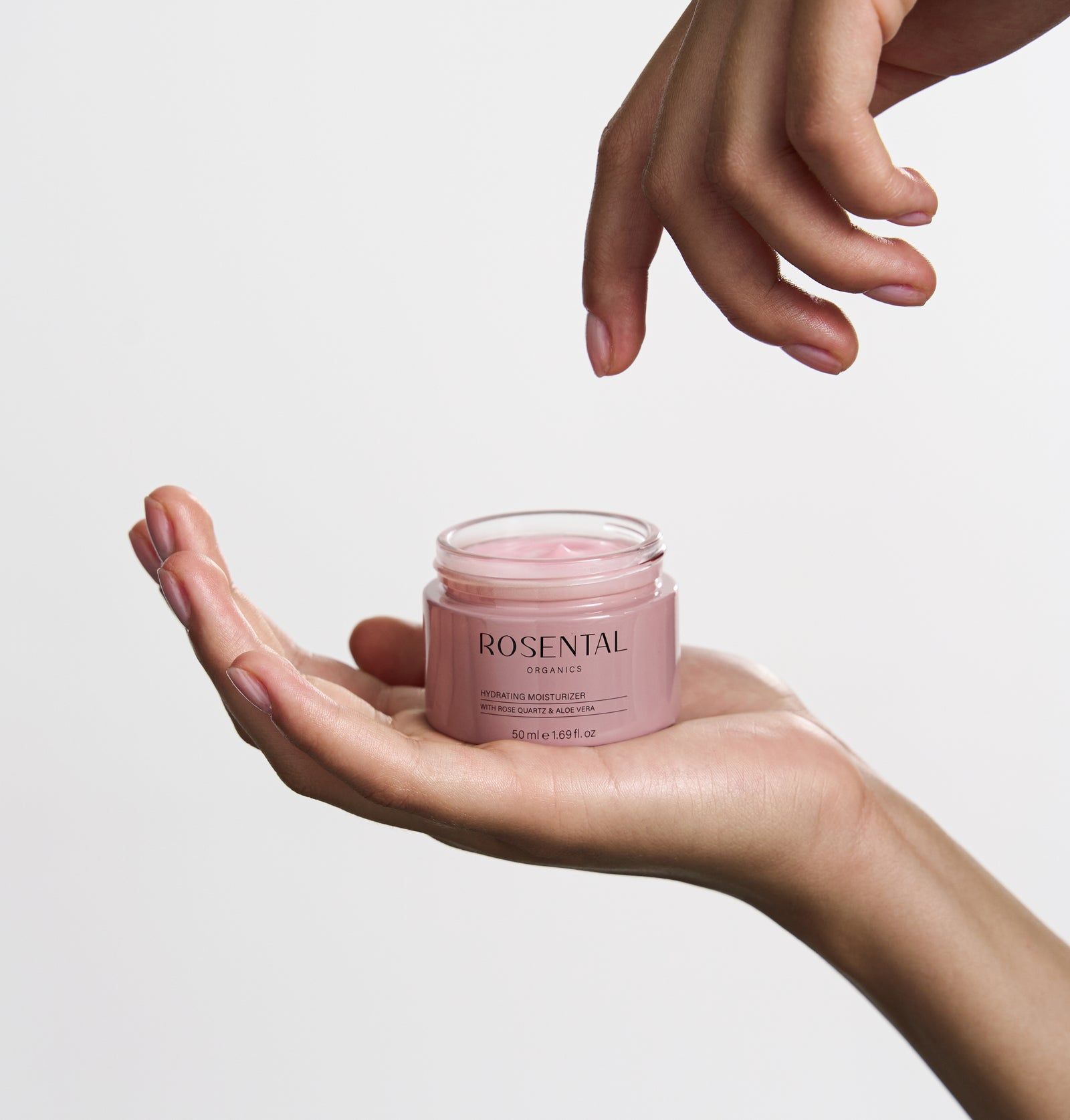 Hände halten ein offenes Glas mit rosa Creme. Aufschrift: Rosental Organics.