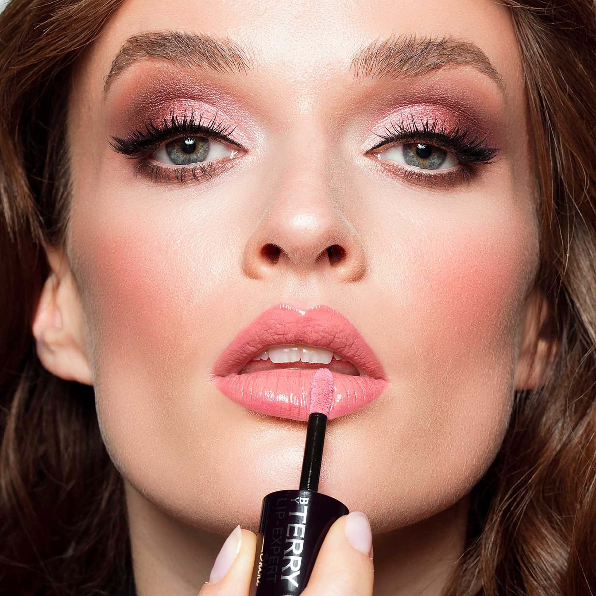 Frau trägt Lipgloss auf. Sichtbar: Lippen, Applikator. Marke: By Terry Lip-Expert Shine.