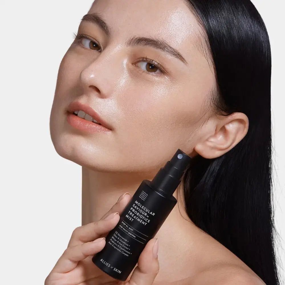Frau hält eine schwarze Sprühflasche mit dem Produktnamen Molecular Saviour Probiotics Treatment Mist.