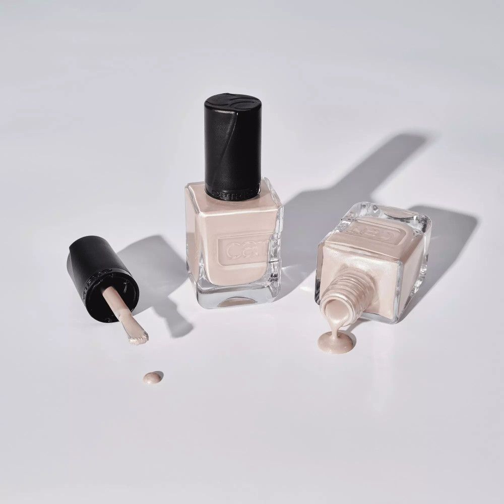 Drei Nagellackflaschen, eine mit geöffnetem Deckel und ausgelaufenem Lack. Der Markenname Catrice ist sichtbar.