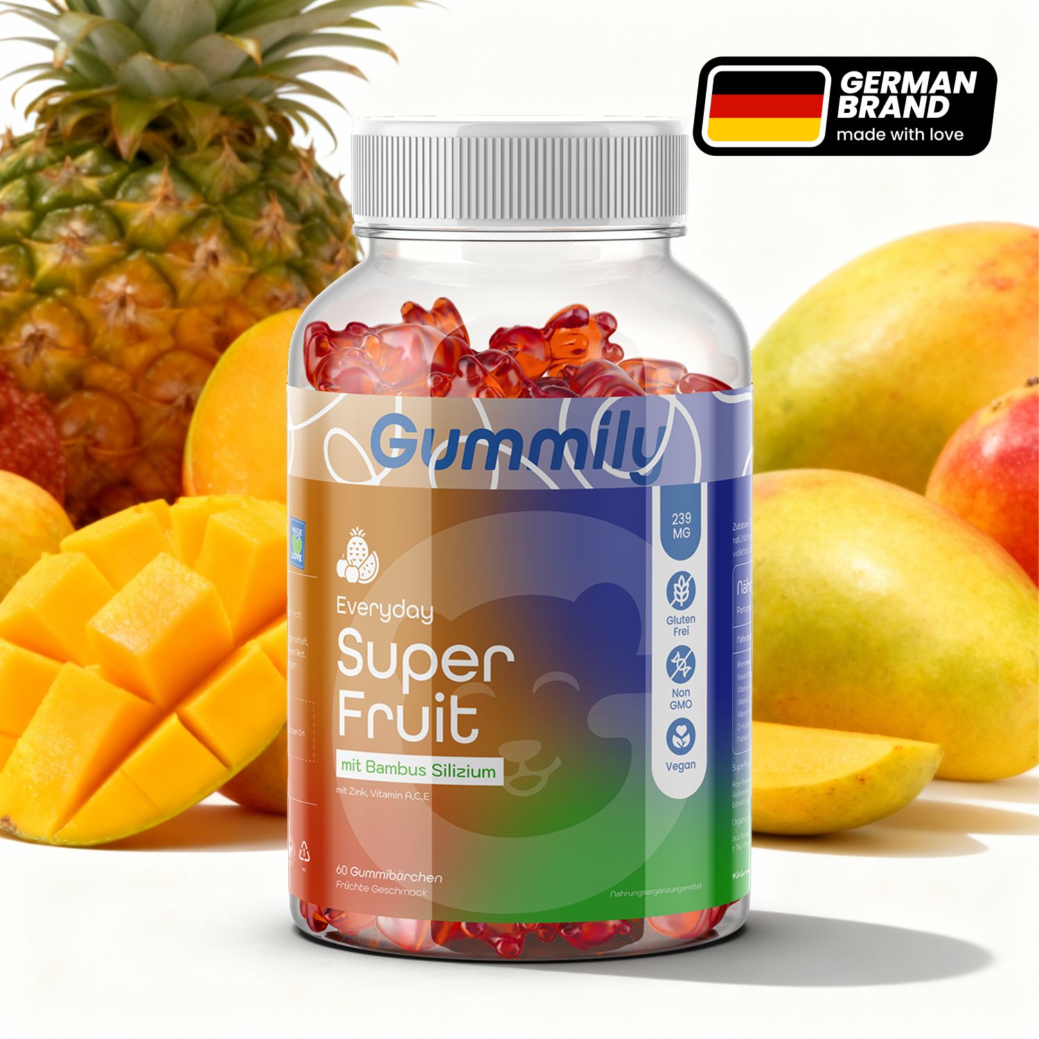Glasflasche mit Gummibärchen. Aufschrift: Gummily Super Fruit. Mit Bambussilika. Umgeben von Früchten wie Mango und Ananas.