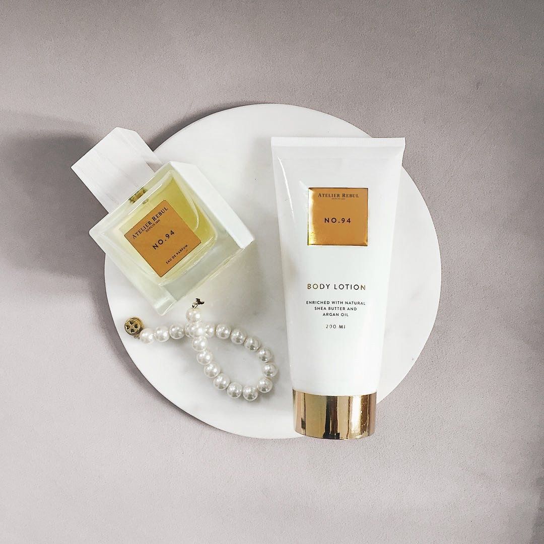 Parfümflakon und Bodylotion auf weißer Platte. Flakon mit Aufschrift "NO. 94". Bodylotion-Tube mit goldener Kappe.