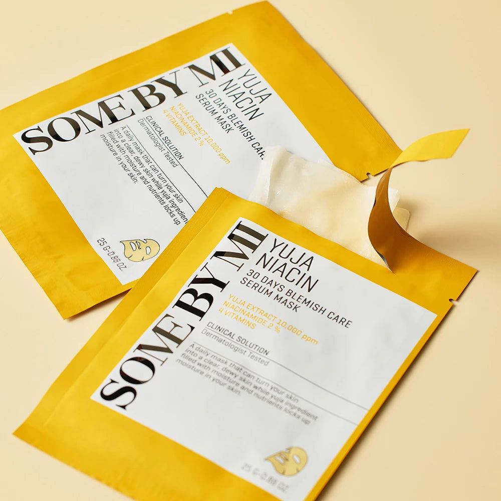 Zwei gelbe Produktverpackungen mit weißem Text. Eine Verpackung ist teilweise geöffnet. Aufschrift: Yuja Niacin Serum Mask.