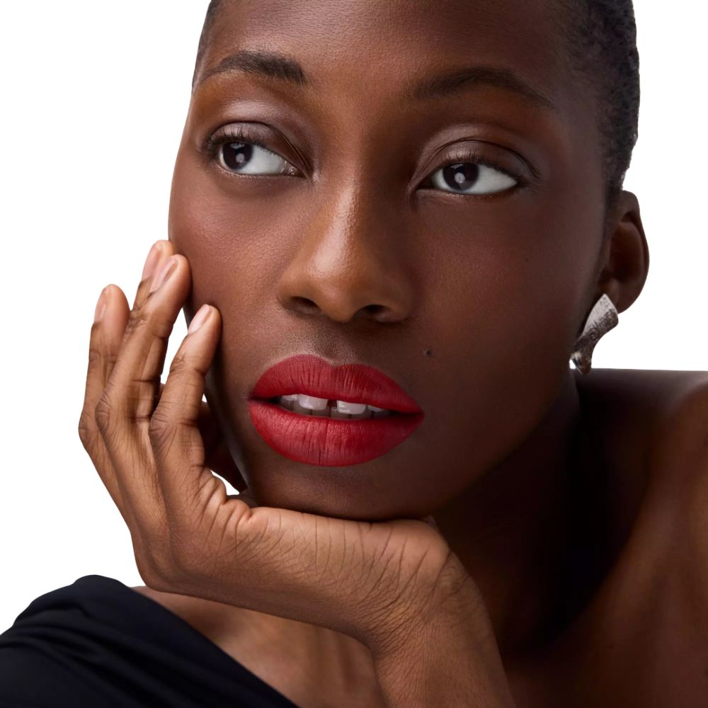 Porträt einer Frau mit rotem Lippenstift. Sie stützt das Kinn auf die Hand.