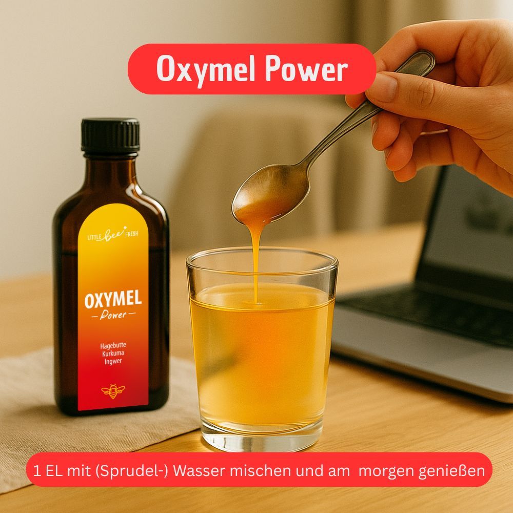 Glasflasche und Glas mit gelber Flüssigkeit. Löffel mit Flüssigkeit. Text: Oxymel Power. Text: 1 EL mit (Sprudel-) Wasser mischen und am morgen genießen.