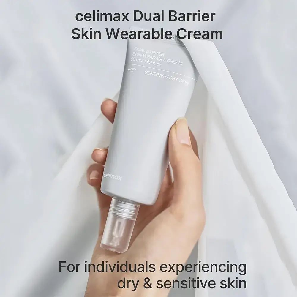 Hand hält eine graue Tube. Aufschrift: celimax Dual Barrier Skin Wearable Cream. Für trockene & empfindliche Haut.