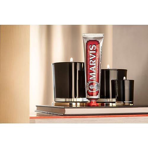 Zahnpasta-Tube MARVIS Cinnamon Mint neben schwarzen Kerzen. Silberne Tube mit rotem Schriftfeld.