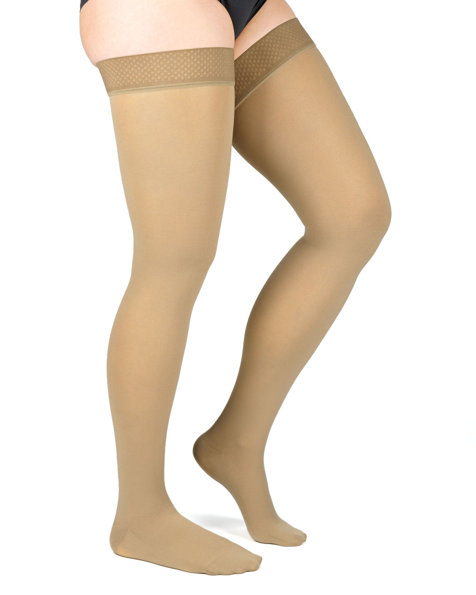 Hautfarbene Kompressions-Schenkelstrümpfe. Oben mit Haftband. Blick von der Seite auf Beine einer Person. Strümpfe reichen bis zum Oberschenkel.