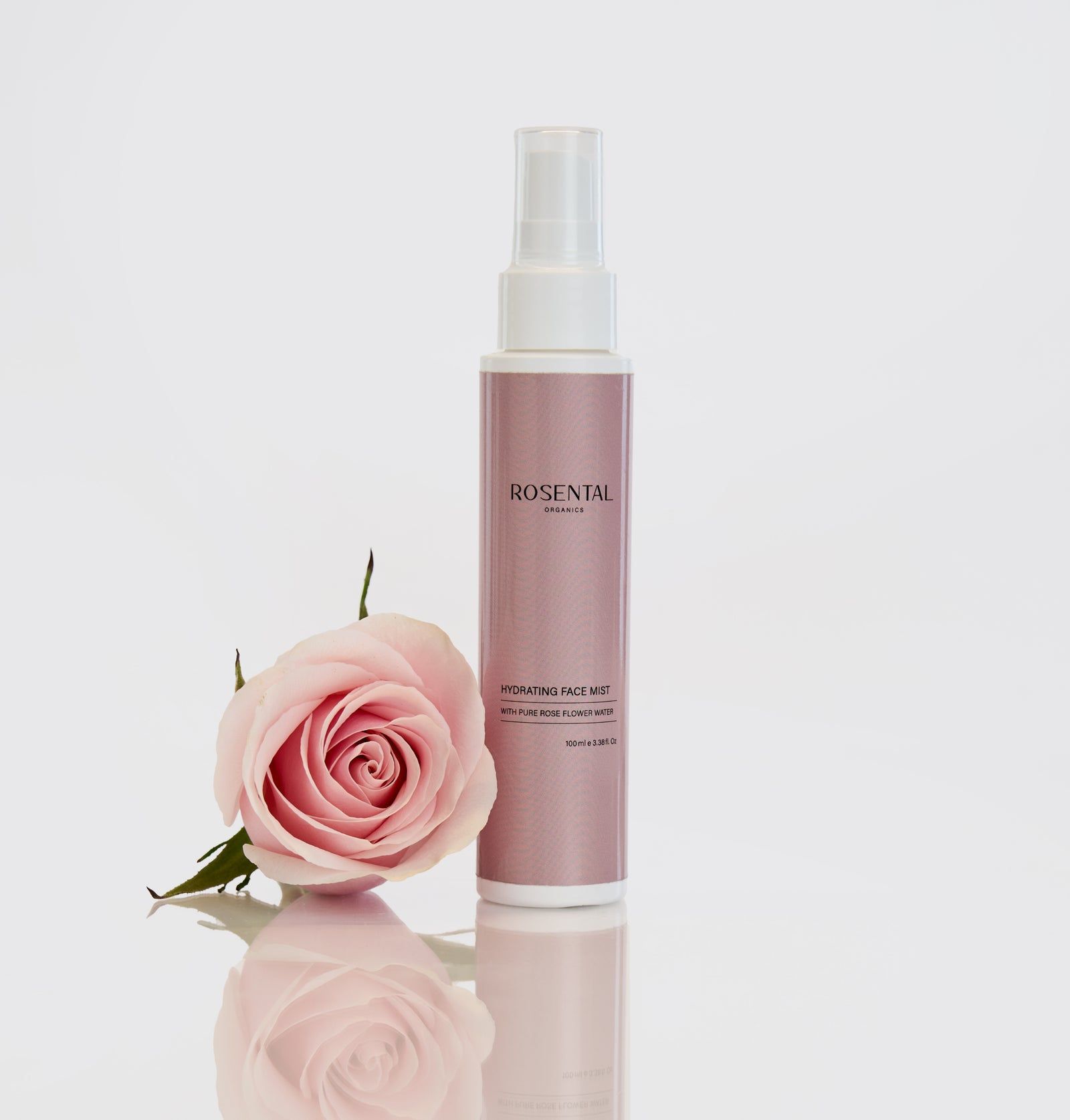 Rosental Organics Hydrating Face Mist Flasche neben einer Rose. Rosa Etikett mit weißem Sprühkopf. Text: Hydrating Face Mist.