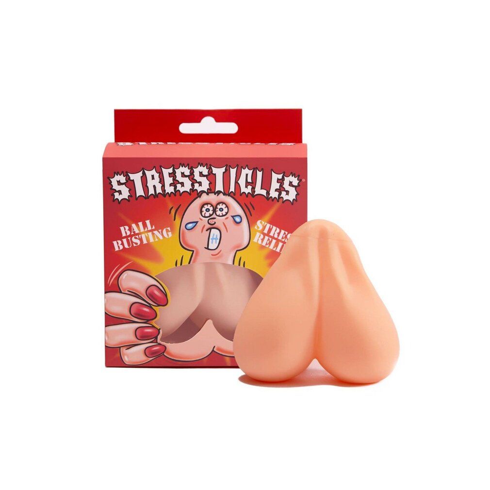 Beige Stressticles neben roter Verpackung. Aufschrift: STRESSTICLES, BALL BUSTING, STRESS RELIEF. Produkt aus Gummi.