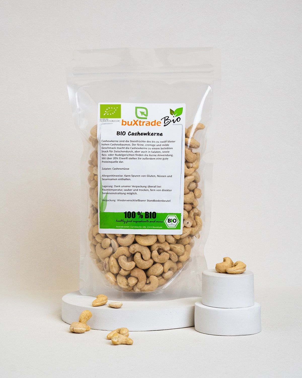 Verpackung buxtrade Bio Cashewkerne neben weißen Podesten.