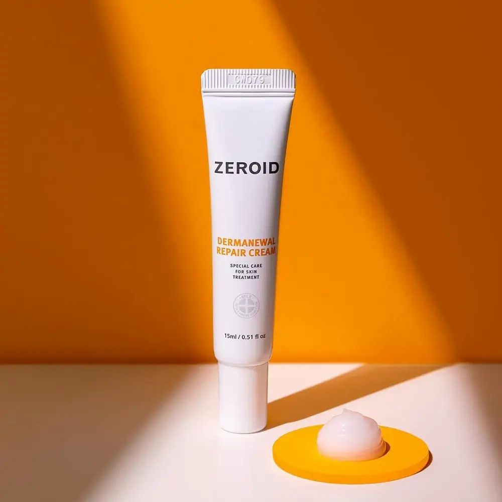 ZEROID Dermanewel Repair Cream Tube. Weißes Design. Produktname und Details sichtbar. 15ml/0.51 fl oz. Gelbe Unterlage.