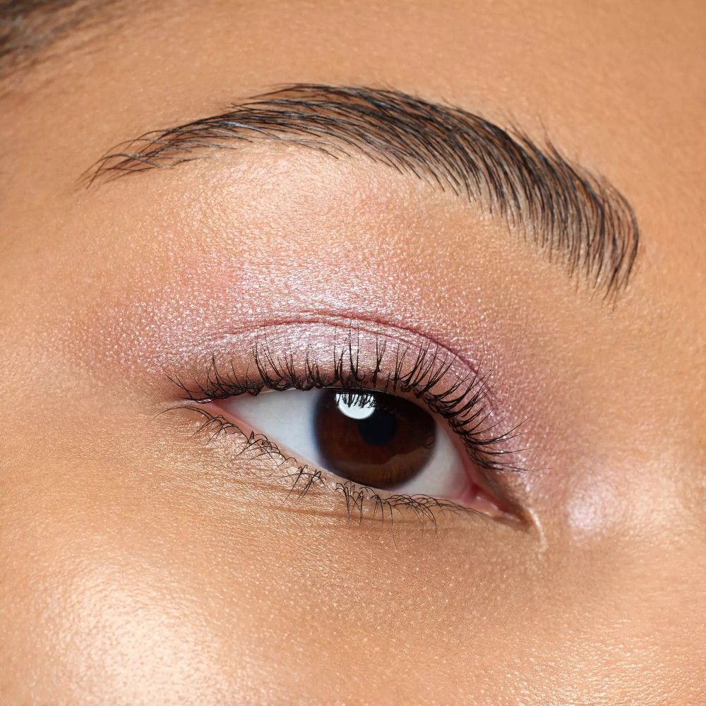 Nahaufnahme eines Auges mit rosa Lidschatten. Sichtbar sind Wimpern und Augenbrauen.