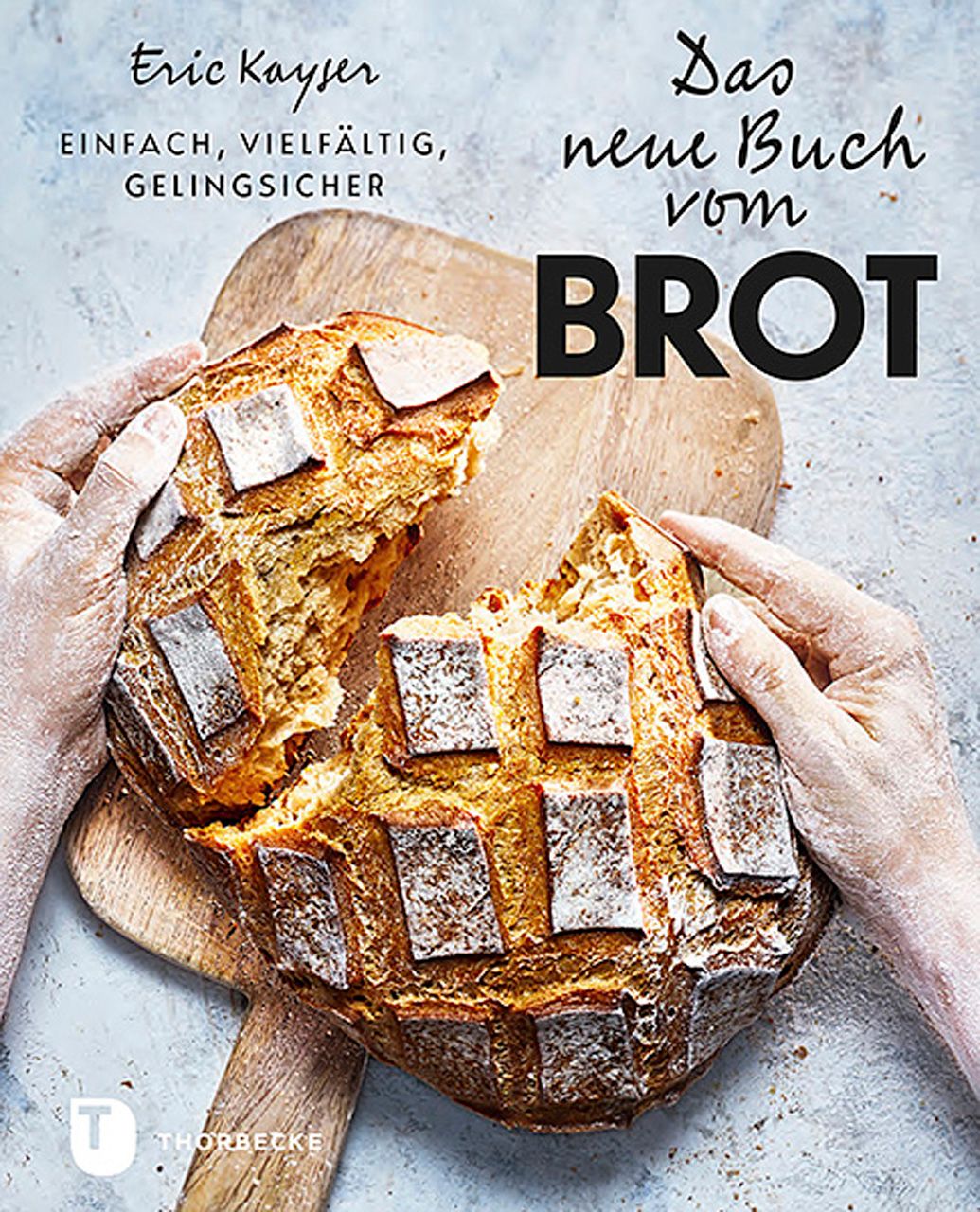 Buchcover mit Brot. Titel: Das neue Buch vom Brot. Autor: Eric Kayser. Auf Holzbrett, von Händen gehalten.
