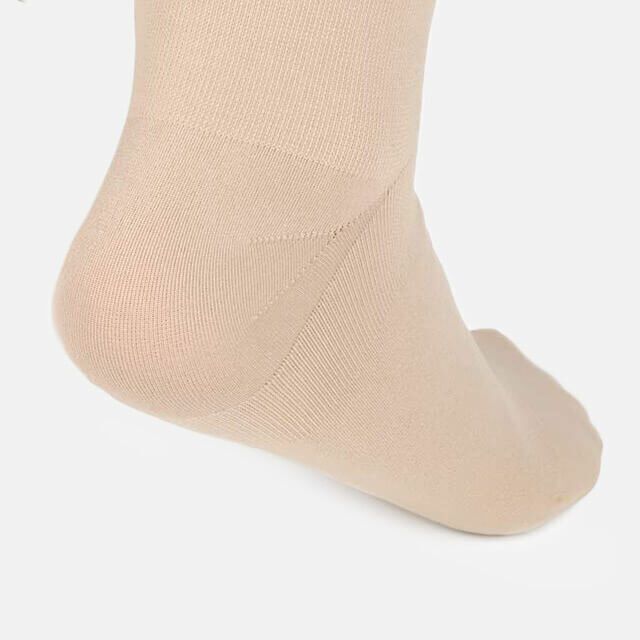Nahaufnahme der Ferse in einem beigen Kompressionsstrumpf. Detail der Ferse.