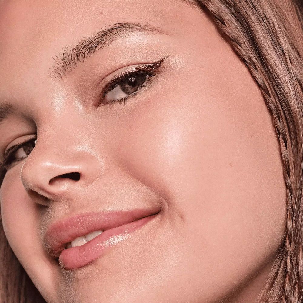Nahaufnahme einer Frau mit metallischem Eyeliner. Sichtbar: Augen, Lippen, Haut.
